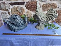 Rooster and swan resin planters on table with yardstick for scale