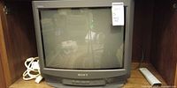 Front view of Sony Trinitron CRT television with cords and remote visible