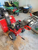 Left front view showing auger housing, engine, tires, handles