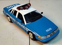 Die-cast Ford Crown Victoria NYPD car angled view showing body, roof light bar, markings