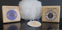 Front view of two boxed L'Occitane soaps and white bath pouf