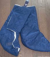 Pair of navy quilted foot protectors folded together, tag visible
