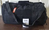 Full view of VEVOR black tactical duffle bag with strap, manual and tag visible