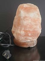 Front view of Himalayan salt lamp on wooden base with cord visible