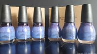Front view of six Sinful Colors Bluz Cruz nail polish bottles