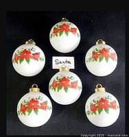 Six white ceramic spherical place card holders with painted red poinsettias, front view