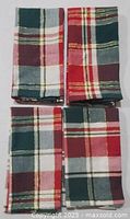 Four stacked plaid napkins showing full set
