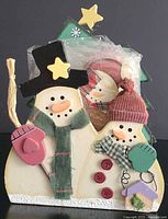 Front view of wooden snowman coaster holder with coasters inside