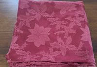 Folded burgundy tablecloth showing poinsettia pattern
