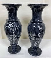 Front view of both black marble vases showing bamboo and plum blossom motifs