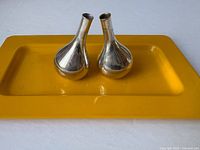 Pair of teardrop silver-tone Dansk candle holders on yellow tray