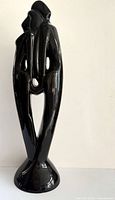 Front view of glossy black ceramic embracing couple sculpture