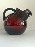 Side view of ruby red round pitcher showing handle and slanted spout