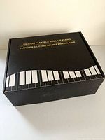 closed black retail box marked 'Silicon Flexible Roll Up Piano'