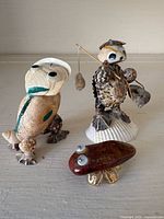 Front view of three shell and rock figurines