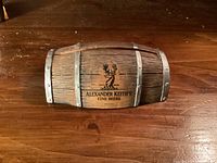 Front view of wooden half-barrel card holder showing logo