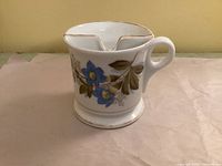 Side view showing floral decal, handle and base