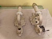 Front view of both white cast iron sconces with candle sleeves