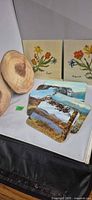 Overall group: wood slices, embroidered linen squares, stack of landscape cork-backed placemats