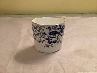 Front view showing blue peacock design and gold-edged scalloped rim