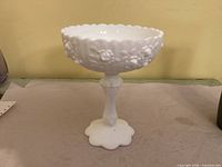 Side view of milk glass pedestal compote showing Cabbage Rose pattern and scalloped rim