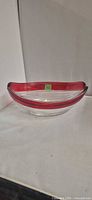 Side view of clear oval glass bowl with red rim