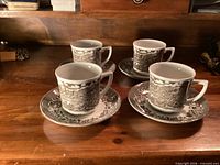 Set of four cups with saucers on wooden surface