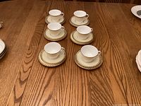 Six teacups on saucers displayed on wooden table
