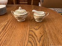 Front view of covered sugar bowl and creamer showing pattern and shape
