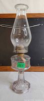 Full view of assembled glass oil lamp showing base, font, burner, wick, and chimney