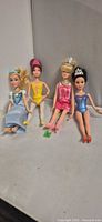 Front view of four Barbie dolls seated