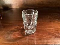 Front view of shot glass showing Queen's logo