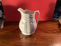 Front view of white ironstone creamer showing wheat relief and shape