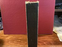 Spine view of the dark green cloth hardcover showing series title and wear at spine top