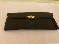 Front view of black suede clutch with flap closed and gold-tone clasp visible