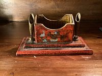 front view showing painted motif, brass pen holders, stepped base