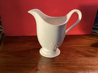 Front view of white ceramic J & G Meakin footed creamer