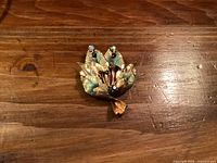 Front view of gold-tone leaf and flower brooch with rhinestones visible