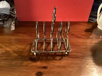 Front view of metal toast rack showing four slice dividers and ball feet