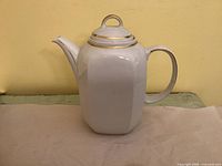 Full side view of porcelain pot showing shape, spout, handle, gold accents