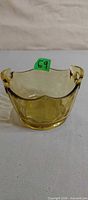 Angled front view of yellow depression glass bowl showing handles and shape