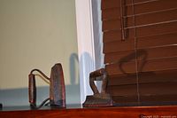 Front view of both cast iron andirons on shelf