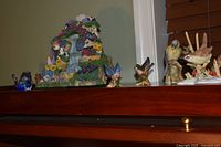 Group of bird figurines and resin waterfall birdhouse music box on shelf