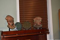 Two clay masks and two wax calendar discs displayed on shelf