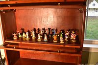 Wide shot of interior cabinet shelf displaying all 25 figurines