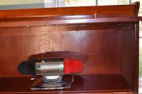 Dremel shoe polisher on shelf with red and black pads visible