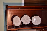 Wide view of three off-white Frankoma nativity plates on shelf