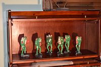 Six wooden frog figurines lined in cabinet