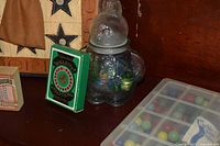 Glass rabbit jar with marbles, green Roulette box, partial tic-tac-toe board, plastic marble case