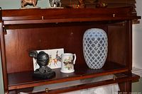 Shelf showing lattice vase, knight bust, tankard, military cards